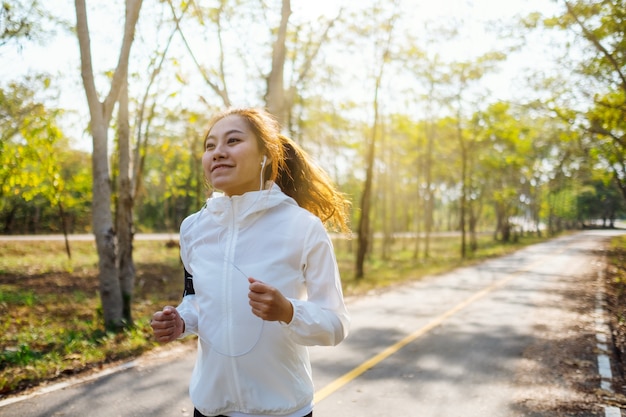 Une jeune femme asiatique jogging dans le parc de la ville le matin