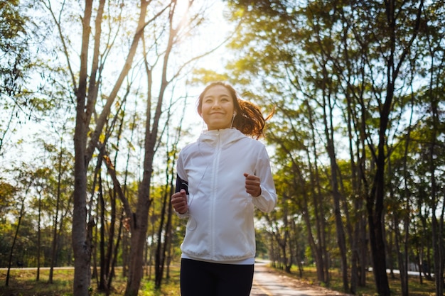 Une jeune femme asiatique jogging dans le parc de la ville le matin