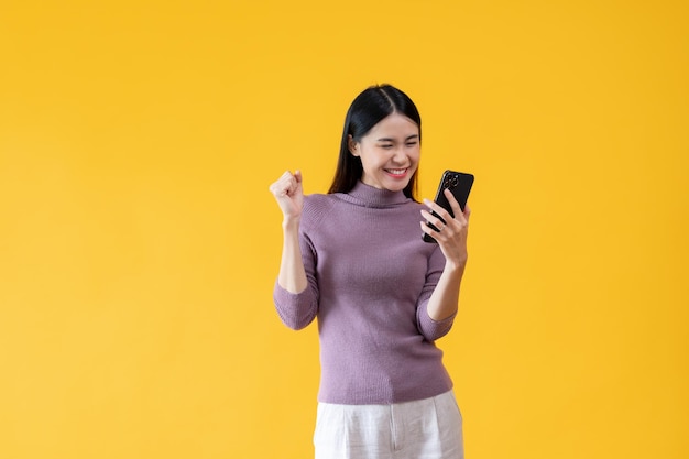 Une jeune femme asiatique joyeuse regarde son smartphone avec un visage heureux