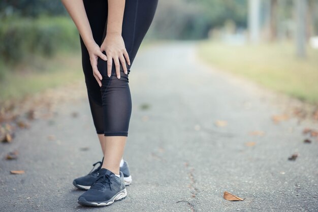Une jeune femme asiatique a mal aux genoux après avoir couru.