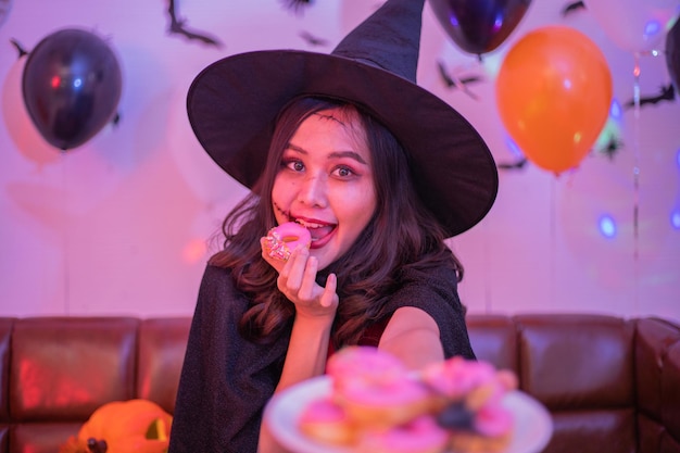 Jeune femme asiatique mangeant des beignets en costumes célébrant halloween