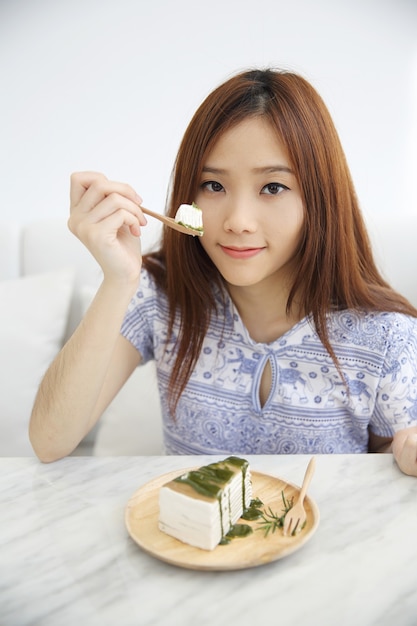 Jeune femme asiatique, manger des aliments sucrés gâteau aux crêpes de thé vert