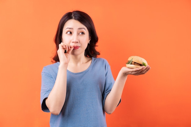 Jeune, femme asiatique, manger, hamburger, sur, orange