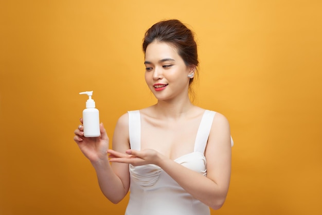 Jeune femme asiatique montrant un produit de beauté à portée de main