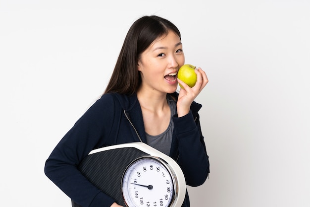 Jeune femme asiatique sur mur blanc avec machine de pesage et avec une pomme