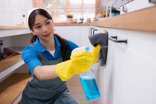 Jeune femme asiatique nettoyant le placard des comptoirs dans le concept de travaux ménagers de cuisine