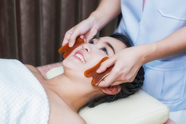 Jeune femme asiatique ont un traitement guasha visage à la clinique de beauté asiatique