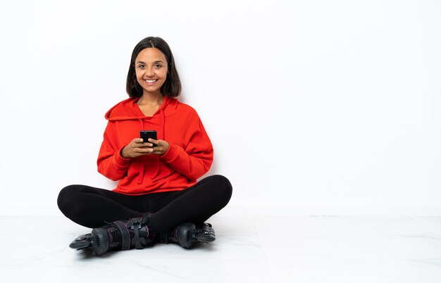 Jeune femme asiatique avec des patins à roulettes sur le sol en envoyant un message avec le mobile