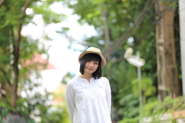 Jeune femme asiatique pensant et regardant le portrait de concept de voyage avec le fond vert d'arbre