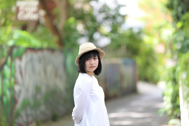 Jeune femme asiatique pensant et regardant le portrait avec le fond vert d'arbre