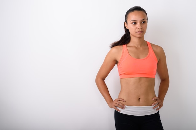 Jeune femme asiatique pensant tout en posant et prêt pour la salle de sport contre l'espace blanc