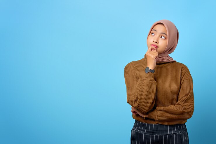 La jeune femme asiatique pensive a l'air de penser sérieusement à une question sur fond bleu