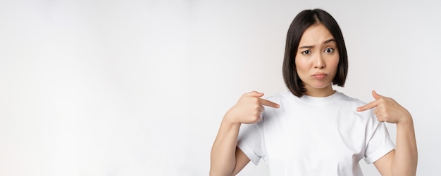 Jeune femme asiatique pointant vers elle-même avec incrédulité choisie surprise par sa candidature