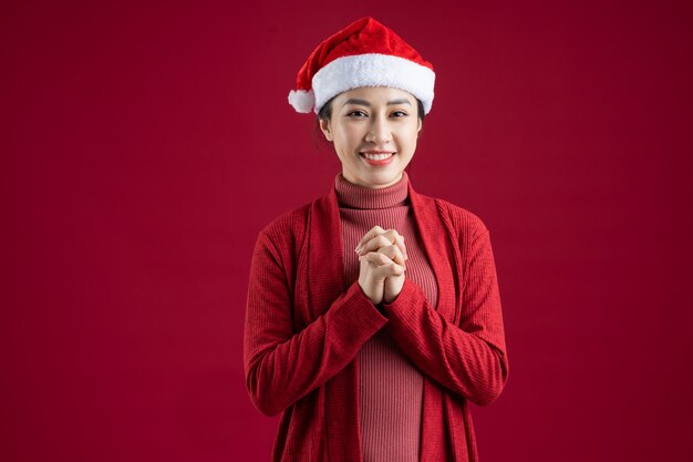 Jeune femme asiatique portant un chapeau de Noël sur fond rouge