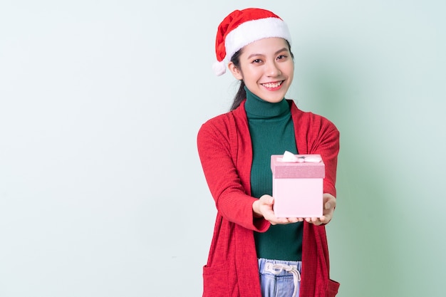 Jeune femme asiatique portant un chapeau de Noël sur fond vert, concept de Noël