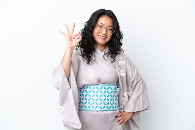 Jeune femme asiatique portant un kimono isolé sur fond blanc montrant un signe ok avec les doigts