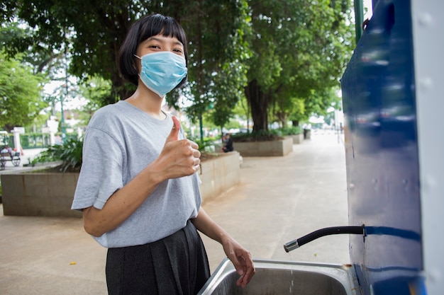 Jeune femme asiatique portant un masque médical se lavant les mains dans l'espace public