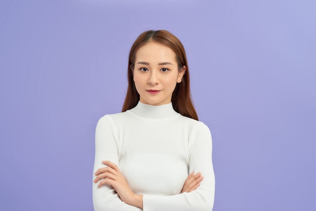 Jeune femme asiatique portant un pull à col roulé debout sur un mur blanc isolé visage heureux souriant avec les bras croisés. Personne positive.