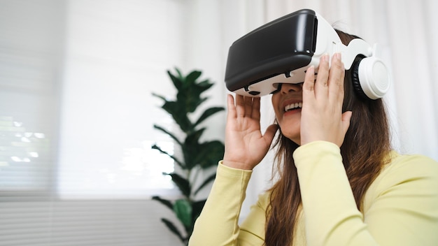 Une jeune femme asiatique portant une réalité virtuelle touchant l'air pendant l'expérience VR Concept de technologie du futur