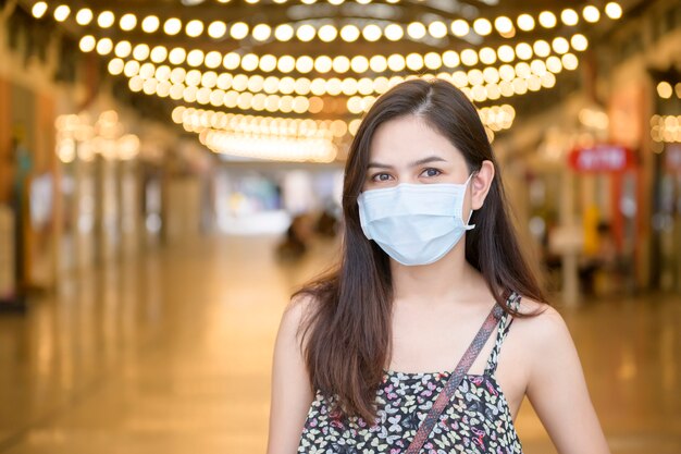 Une jeune femme asiatique porte un masque de protection shopping dans un centre commercial, protection contre les coronavirus, nouveau concept de mode de vie normal