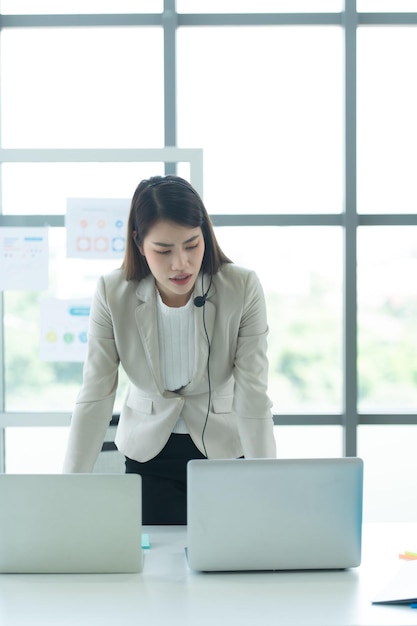 Une jeune femme asiatique qui travaille dans un centre d'appels en tant que consultante sur les investissements en actions.