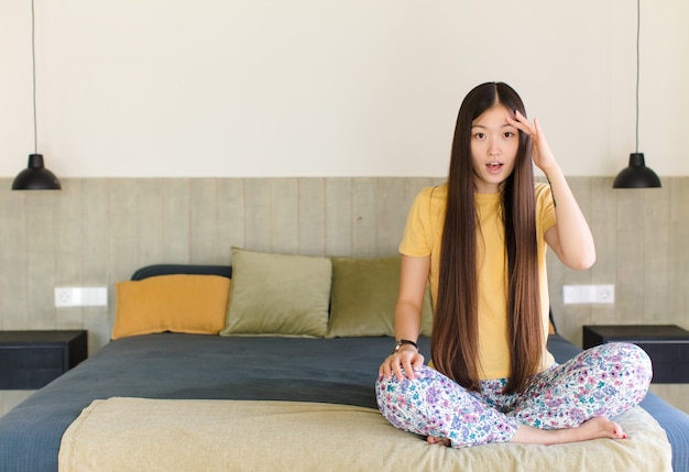 Jeune femme asiatique à la recherche concentrée, réfléchie et inspirée, de remue-méninges et d'imaginer avec les mains sur le front