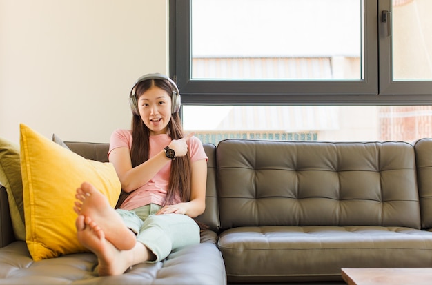 Jeune femme asiatique à la recherche excitée et surprise en pointant vers le côté et vers le haut pour copier l'espace