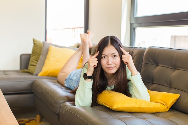 Jeune femme asiatique avec un regard sérieux et concentré, un brainstorming et une réflexion sur un problème difficile