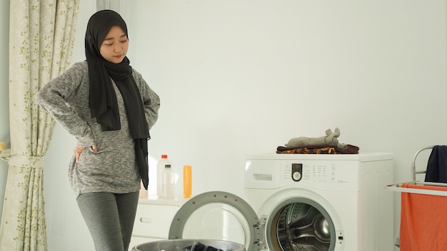 Jeune femme asiatique regardant le panier de vêtements sales à la maison