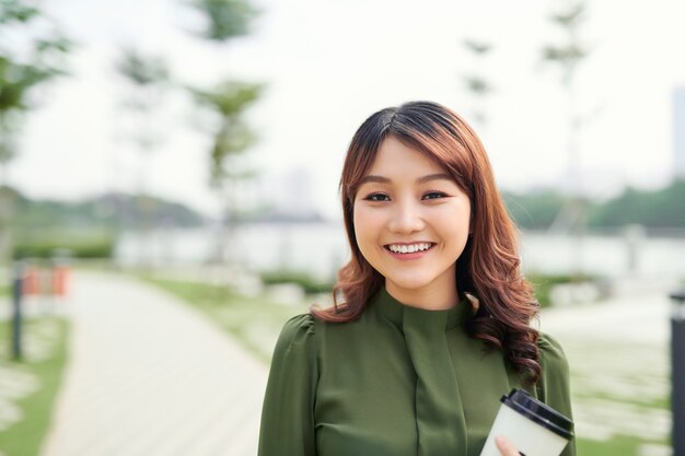 Jeune femme asiatique réussie va travailler avec une tasse de café à emporter