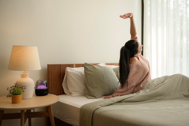 Une jeune femme asiatique s'étendant dans le lit après s'être réveillée le matin.