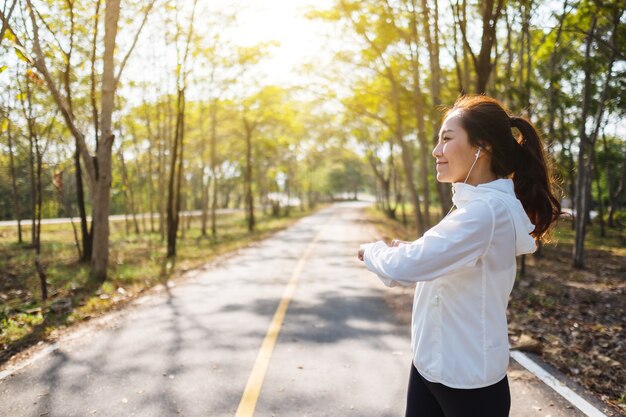 Une jeune femme asiatique s'étire les bras avant de courir dans le parc de la ville