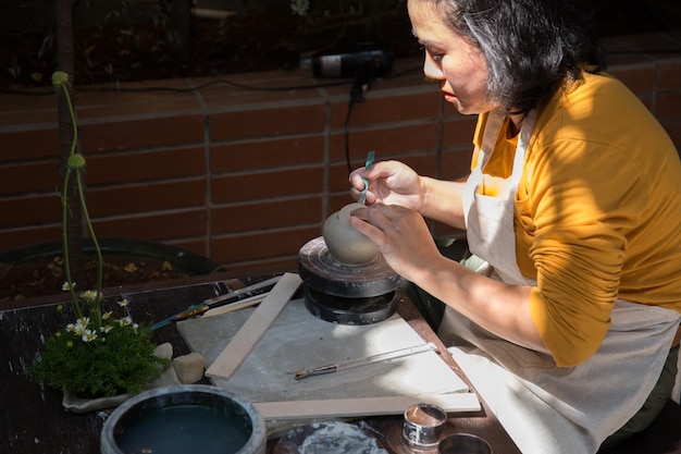 Jeune femme asiatique se concentrant sur son travail à l'atelier de poterie