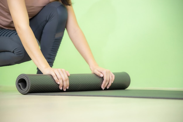 Jeune femme asiatique se concentre sur le tapis de yoga noir après le cours de yoga