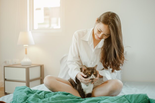 Jeune femme asiatique se réveille rafraîchie le matin en jouant avec des chats au lit joyeusement en vacances. Asiatique, asie, détente, bonheur, rafraîchissement, concept de style de vie.