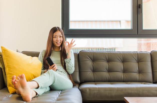 Jeune femme asiatique se sentir heureuse, détendue et satisfaite, montrant son approbation avec un geste correct, souriant