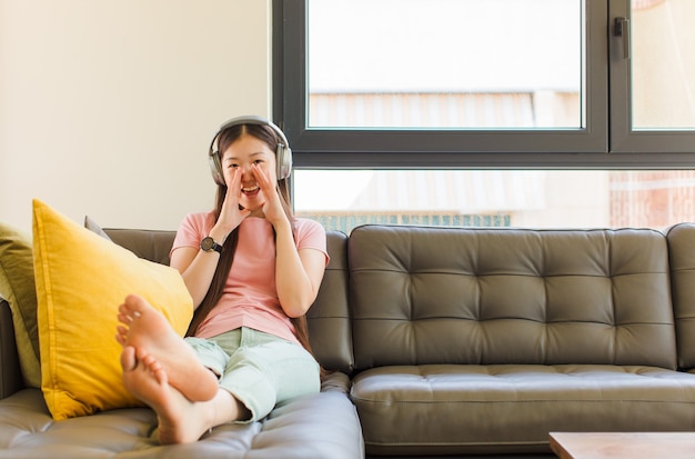 Jeune femme asiatique se sentir heureuse, excitée et positive, donnant un grand cri avec les mains à côté de la bouche, appelant