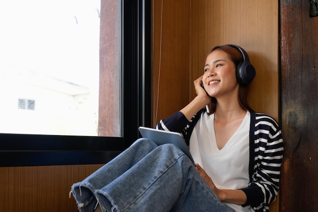 Jeune femme asiatique séduisante avec casque écoutant de la musique sur tablette numérique