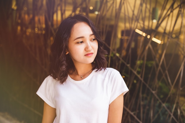 Jeune Femme Asiatique Séduisante Dans Un T-shirt Blanc Calme Ou Triste, Pensant à Quelque Chose Et Regardant Sur Le Côté.