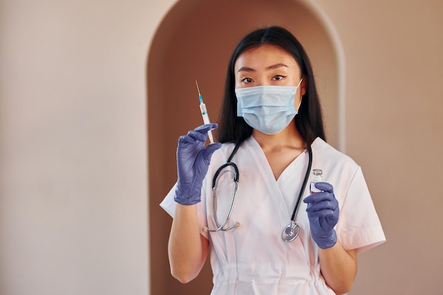 Jeune femme asiatique sérieuse debout à l'intérieur