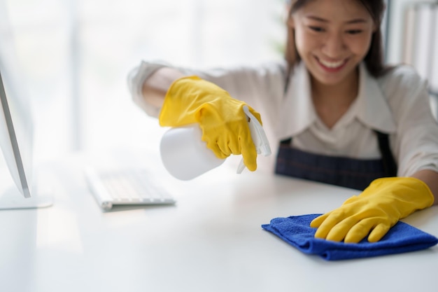 Photo jeune femme asiatique de service de nettoyage ouvrière nettoie la table à la maison belle jeune fille femme de ménage nettoyeuse se sent heureuse et essuyer désordre compteur sale pour le ménage ménage ou les tâches ménagères