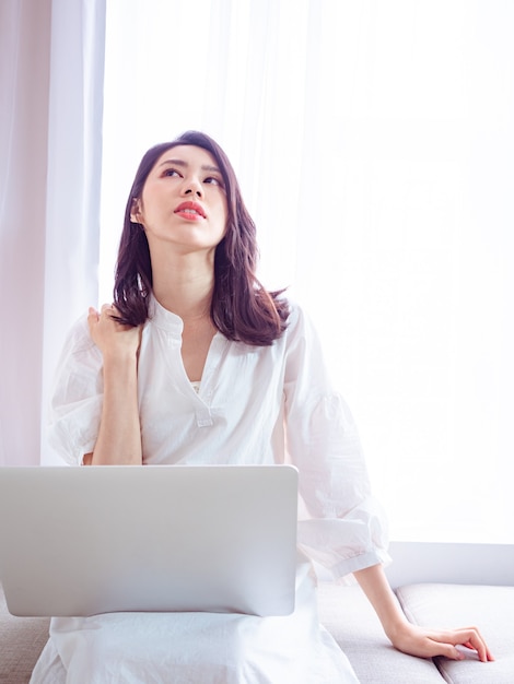 Jeune femme asiatique souffrant de douleurs à l'épaule lors de l'utilisation d'un ordinateur portable