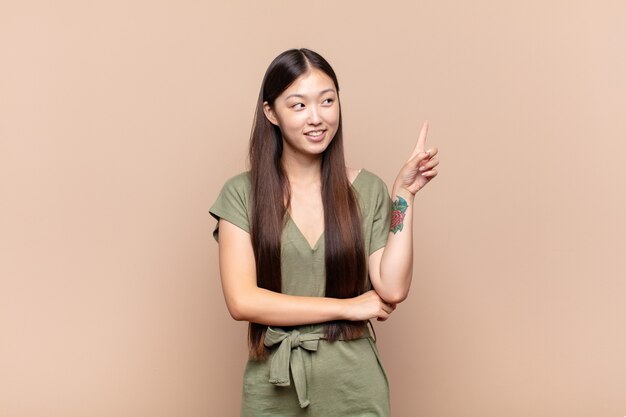 Jeune femme asiatique souriant joyeusement et regardant sur le côté isolé