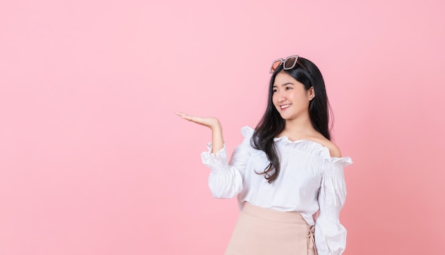 Jeune femme asiatique souriante debout avec les paumes ouvertes