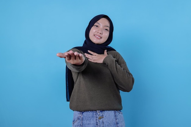 Jeune femme asiatique souriante avec une expression joyeuse, montre quelque chose d'étonnant dans un espace vide dans un tissu décontracté isolé sur un mur jaune. concept d'expression faciale