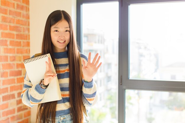 Jeune femme asiatique souriante et à la sympathique, montrant le numéro sept ou septième avec la main en avant, compte à rebours