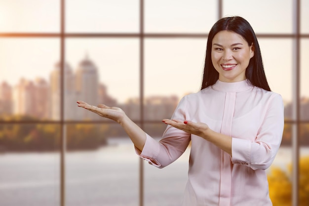 Jeune femme asiatique souriante tenant un espace de copie sur ses paumes