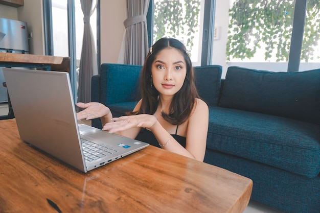 Une jeune femme asiatique sourit assise sur le canapé du salon