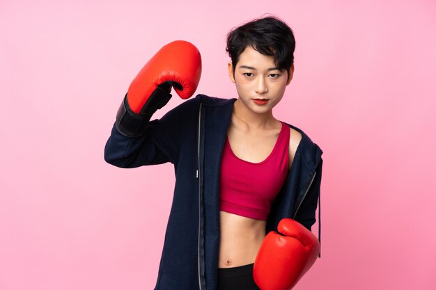 Jeune femme asiatique sport sur mur rose isolé avec des gants de boxe