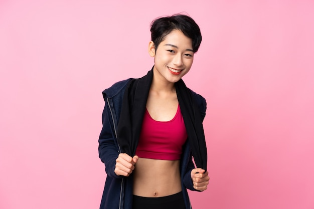 Jeune femme asiatique sport sur mur rose isolé avec serviette de sport